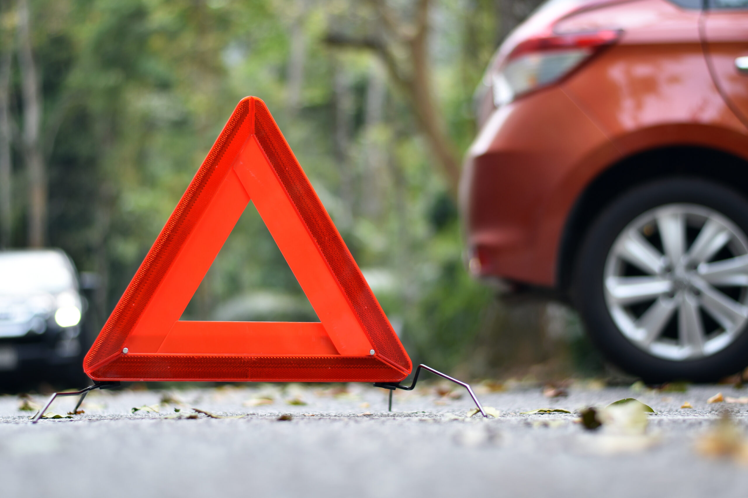 Red,Triangle,Sign,On,Road,Surface,With,Blurred,Orange,Car